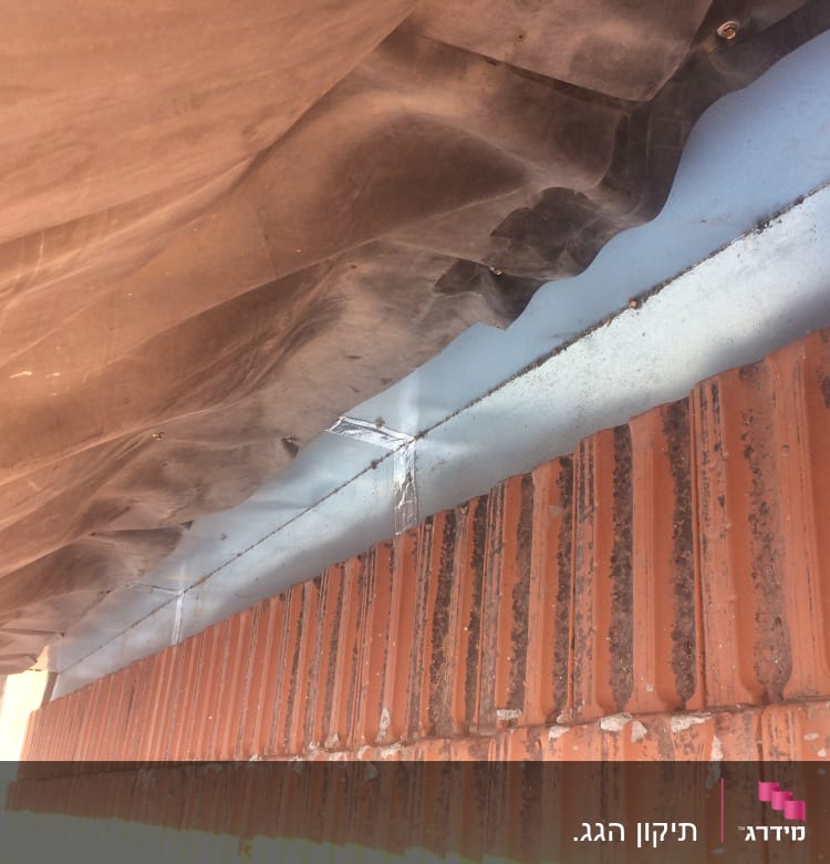 רעפים כתומים עם יריעת פלסטיק כהה על הגג